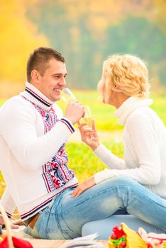 husband and wife drinking champagne from glasses in the park