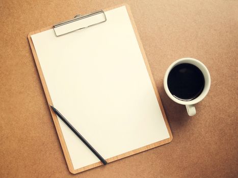 Blank white paper on clipboard with cup of coffee, retro filter effect