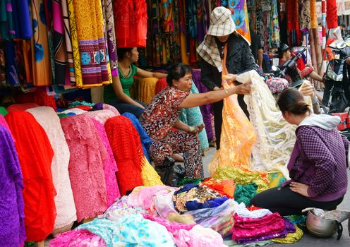 HO CHI MINH CITY, VIET NAM- DEC 28: Asia fabric market, colorful roll of cloth for clothing show at store, Vietnamese woman choice at shop, garment industry develop to export, Vietnam, Dec28, 2014