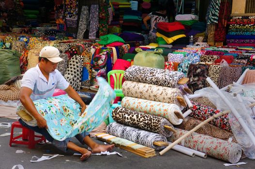 HO CHI MINH CITY, VIET NAM- DEC 28: Asia fabric market, colorful roll of cloth for clothing show at store, Vietnamese worker working at shop, garment industry develop to export, Vietnam, Dec28, 2014