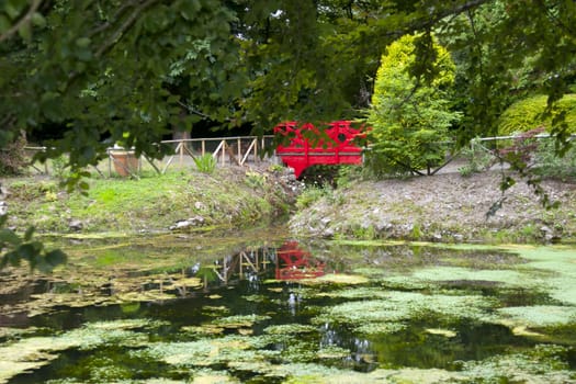 small red bridge on a lovely park walk beside a pond