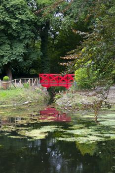 small red bridge on a lovely park walk beside a pond