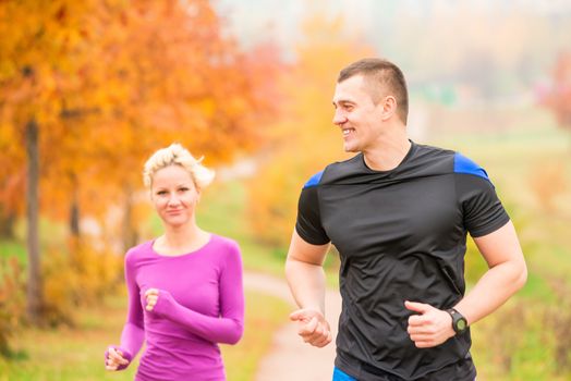 healthy lifestyle - jogging. a man and a woman running in the morning in the park