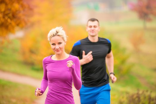 young couple running in the park in autumn morning