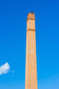 Old brick chimney on the background of clear  blue sky.