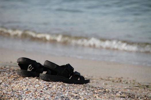 Summer sandals on the Shelly shore near the sea with waves