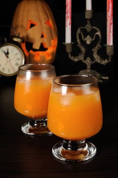 Glass of pumpkin juice with ice on Halloween