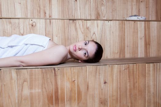 Serious woman lying inside the sauna