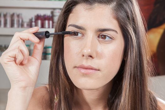 Woman applying mascara on her eyes