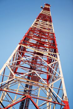 Red and white communication tower on blue sky