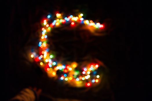 colorful letter C made of blurred circular bokeh on black background