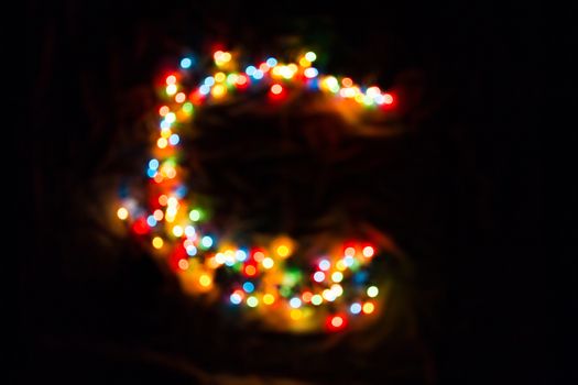 colorful letter C made of blurred circular bokeh on black background