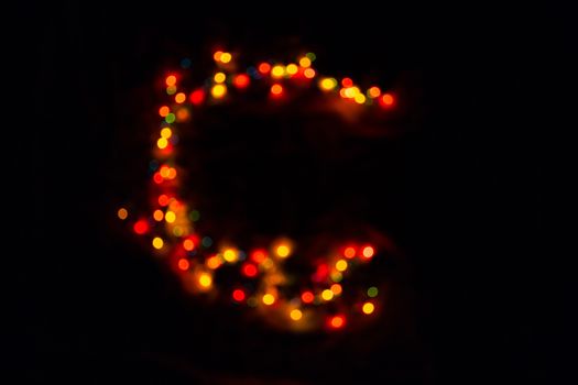 colorful letter C made of blurred circular bokeh on black background