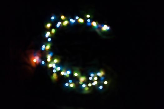 colorful letter C made of blurred circular bokeh on black background