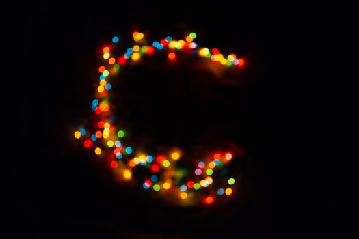 colorful letter C made of blurred circular bokeh on black background