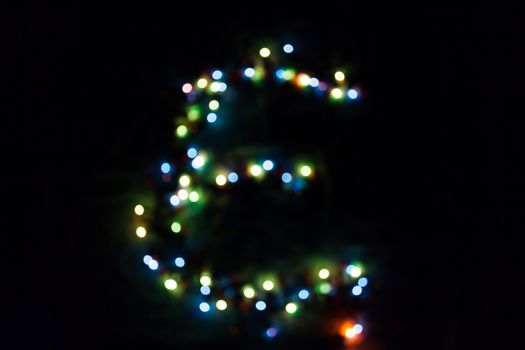 colorful letter E made of blurred circular bokeh on black background