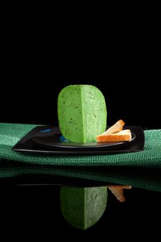 Green gouda cheese isolated on black background. Culinary cheese eating.