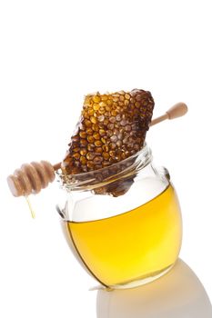 Honey in glass jar with wooden honey spoon and honey comb on white background. Healthy honey eating.
