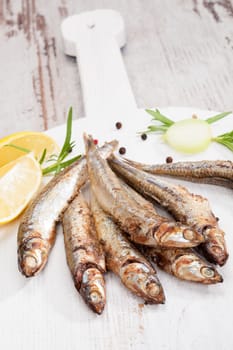 Culinary seafood eating. Grilled sardines on wooden background with fresh herbs and lemon. Culinary mediterranean eating. 