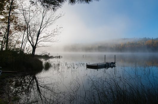 Early morning sunrise burns off the fog which has lingered over the lake.