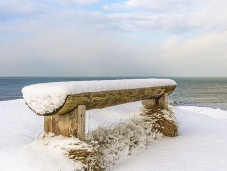 wooden bench covered with snow on the shore of the Baltic Sea, Ventspils, Latvia