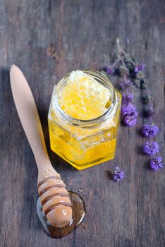 honeycomb and honey in glass jar and wild mint on old wooden background