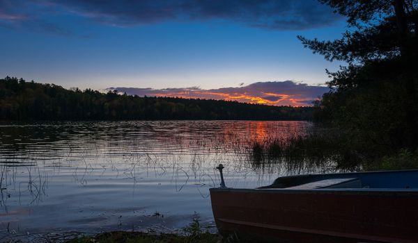 Colourful clouds are reflected on a lake at sundown.