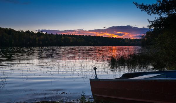 Colourful clouds are reflected on a lake at sundown.