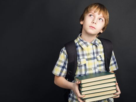 Portrait of diligent student in glasses with heap of books in hands