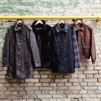 Men's trendy clothing on hangers on grunge brick wall. Concept background