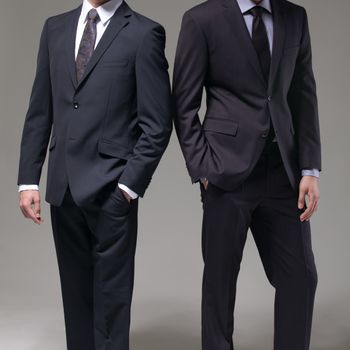 Two men in elegant suit on a dark background
