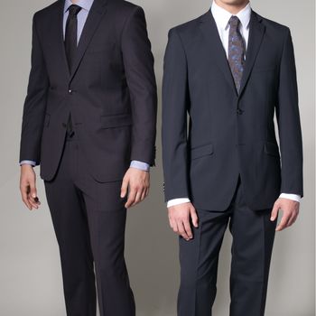 Two men in elegant suit on a dark background