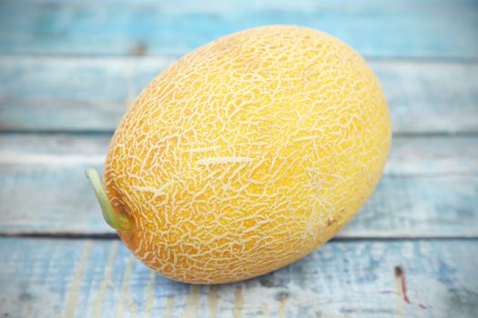 one whole fresh ripe melon on a wooden background