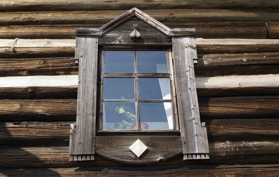 Old window on the wall of a wooden old house.