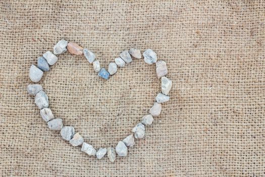 Heart made of stones  on gunnysack, background, with copyspace