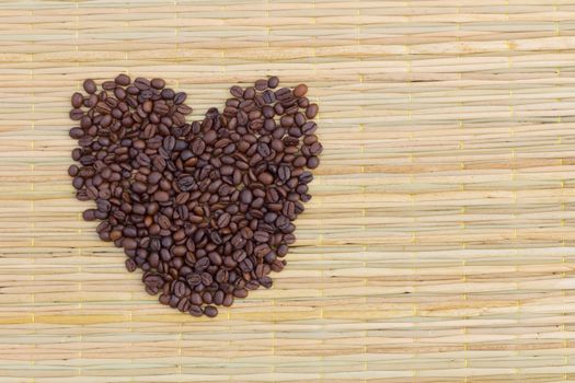 heart from coffee beans on traditional mat, with copyspace on the right