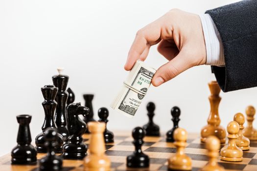 Business man hand holding dollar currency unfair playing chess game