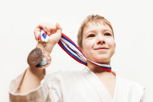 Martial art sport success and win concept - smiling karate champion child boy hand holding first place victory gold medal award