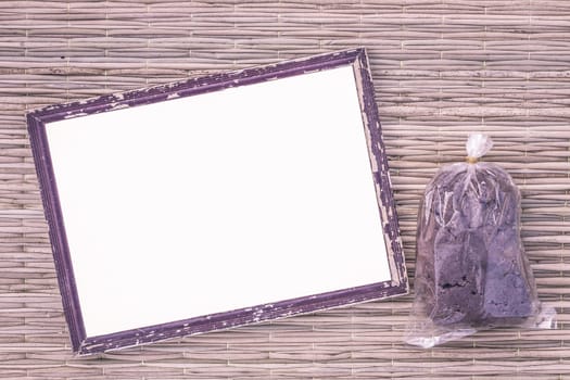 wooden old black picture frame on traditional mat with white space in the middle with shrimp paste in plastic bag, vintage filter