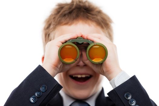 Little smiling child boy in business suit hand holding binoculars lens looking for direction white isolated