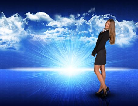 Businesswoman standing against digitally generated spacy blue landscape with rising sun and cloudy sky, looking back over her shoulder, smiling