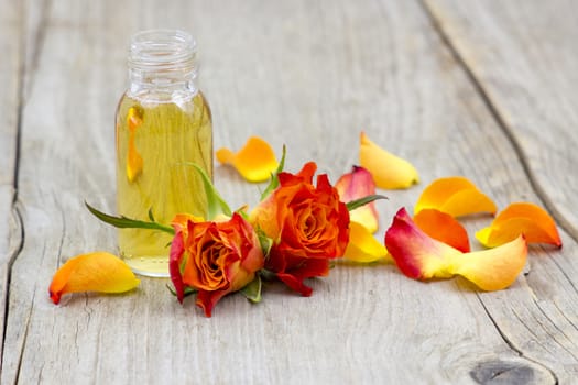 bath oil and orange roses on old wooden background