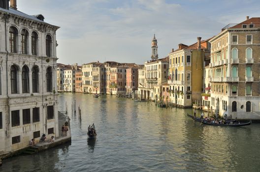 Traditional urban scene with gondolas and some tourists in its promenade in Venice, Italy