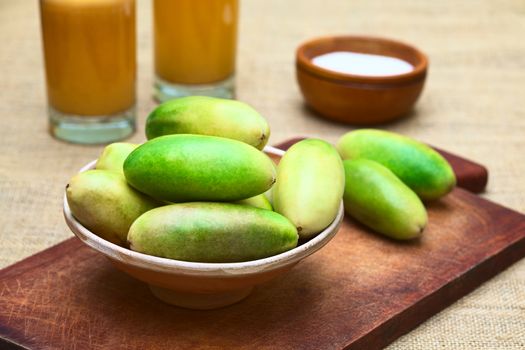 Latin American fruit called banana passionfruit (lat. Passiflora tripartita) (in Spanish mostly tumbo, curuba, taxo) in bowl and banana passionfruit juice in the back (Selective Focus, Focus on the fruits in the front)