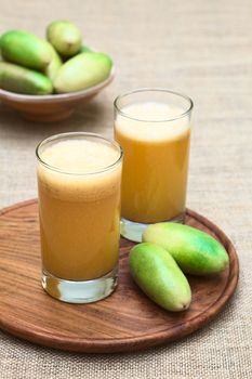 Fresh juice made of the Latin American fruit called banana passionfruit (lat. Passiflora tripartita) (in Spanish mostly tumbo, curuba, taxo) (Selective Focus, Focus on the front of the first glass)