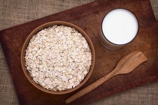 Bowl full of rolled oats with a glass of milk on the side photographed with natural light (Selective Focus, Focus on the top of the oats)