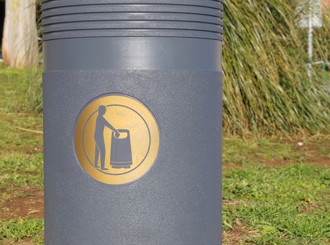 golden sign label on grey trash basket      