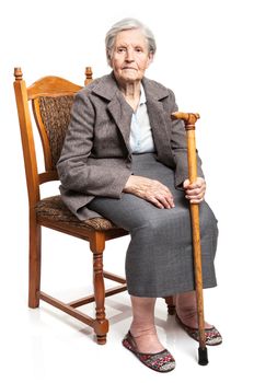 Senior woman with walking stick sitting on chair over white background