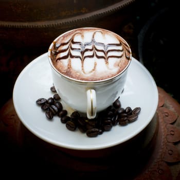 Latte art, coffee in coffee beans and Asian pottery background