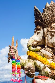 close-up statute of Ganesha outdoor against blue sky and white clouds.